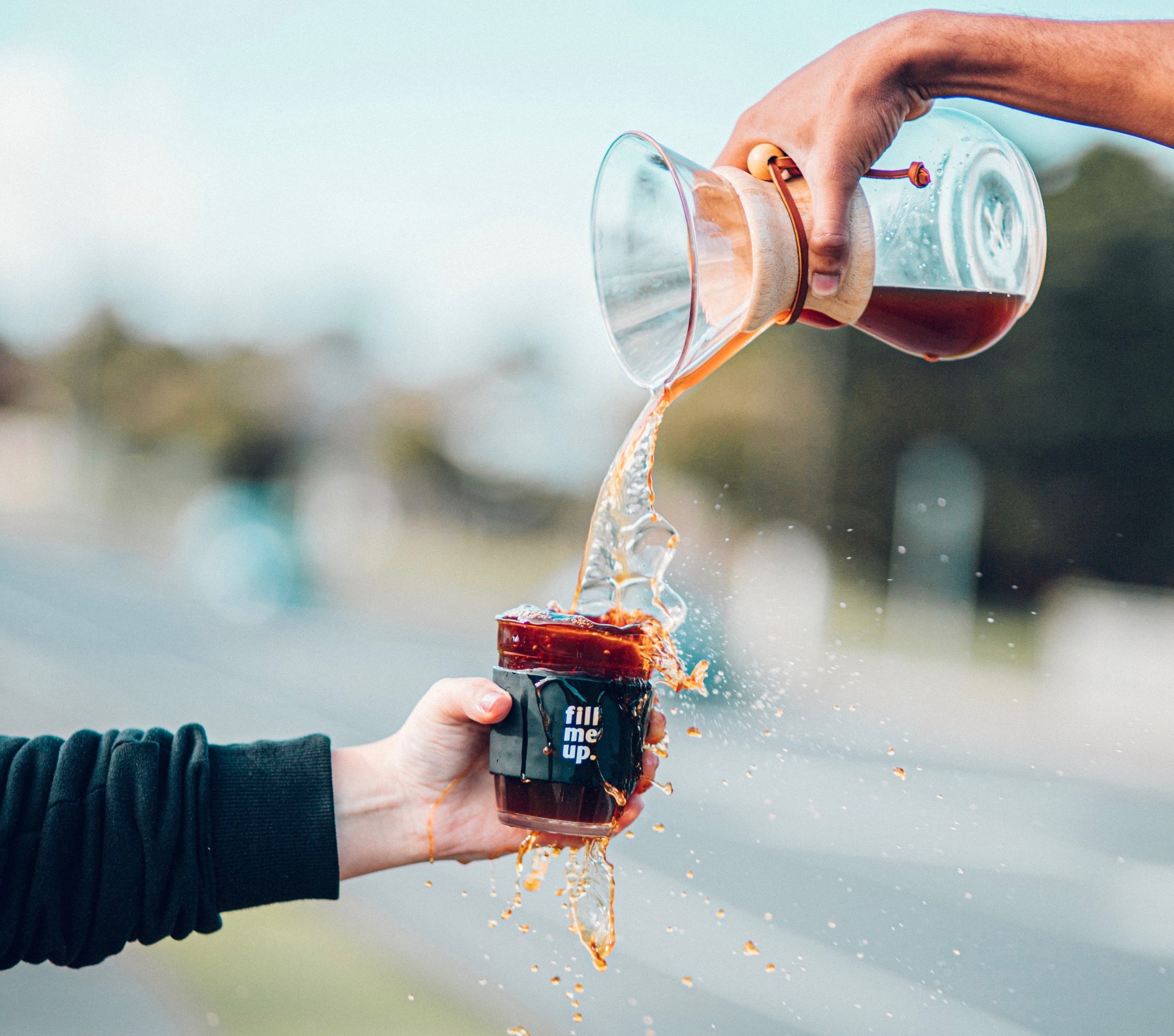 Pouring coffee from a chimex into a reusable cup