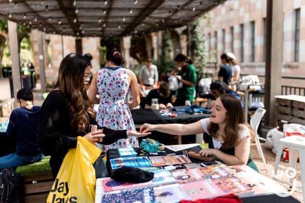 Image of most recent UQ Preloved stall and Repair Café. Photo of student paying for preloved clothes.