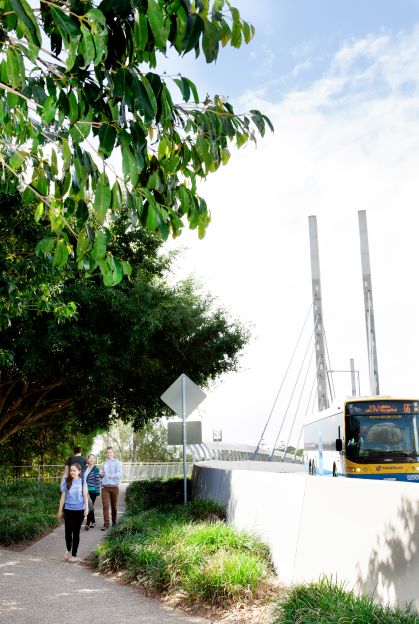 Image of students at the UQ Lakes bus stop, walking over the Green Bridge