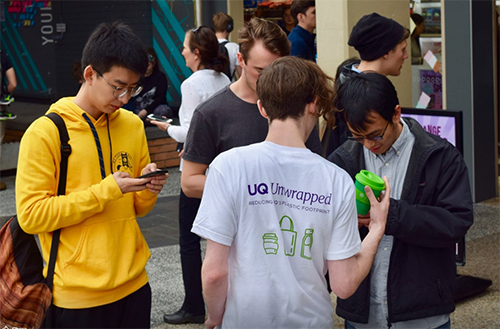 Student with Green Caffeen coffee cups and using the app