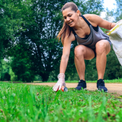 Image of person in active wear and running shoes bending down to pick up litter with gloves and a bag.