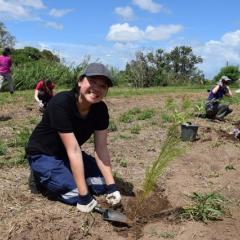 Students sitting on soil with trowel and seedling pots